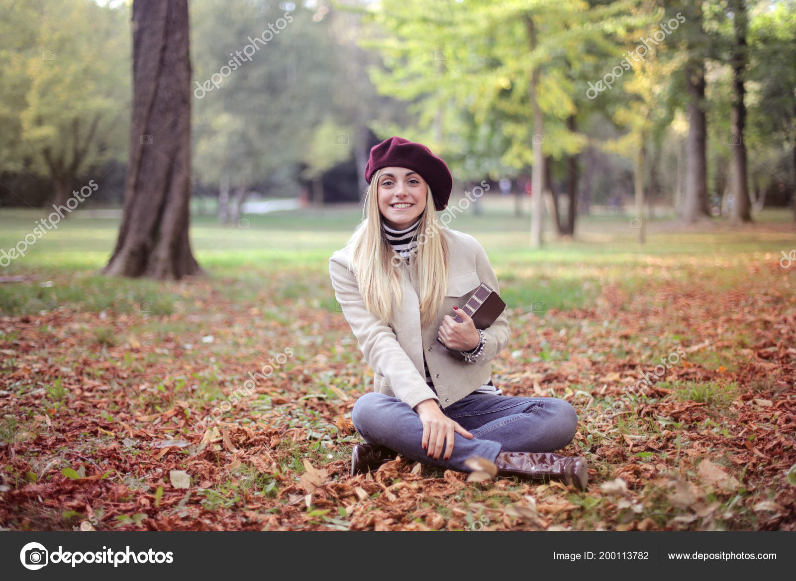 Голая блондинка в парке сидит на желтых листьях