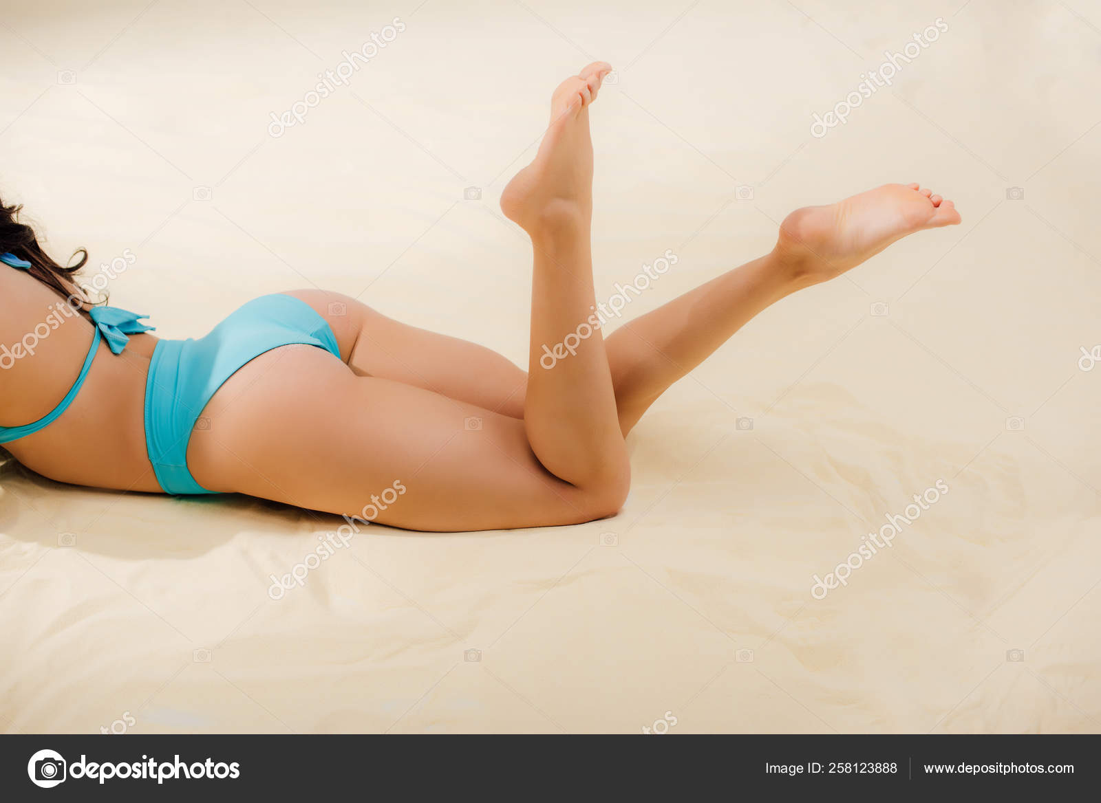 Зрелая женщина в купальнике лежит на пляже и отдыхает попав под камеру
