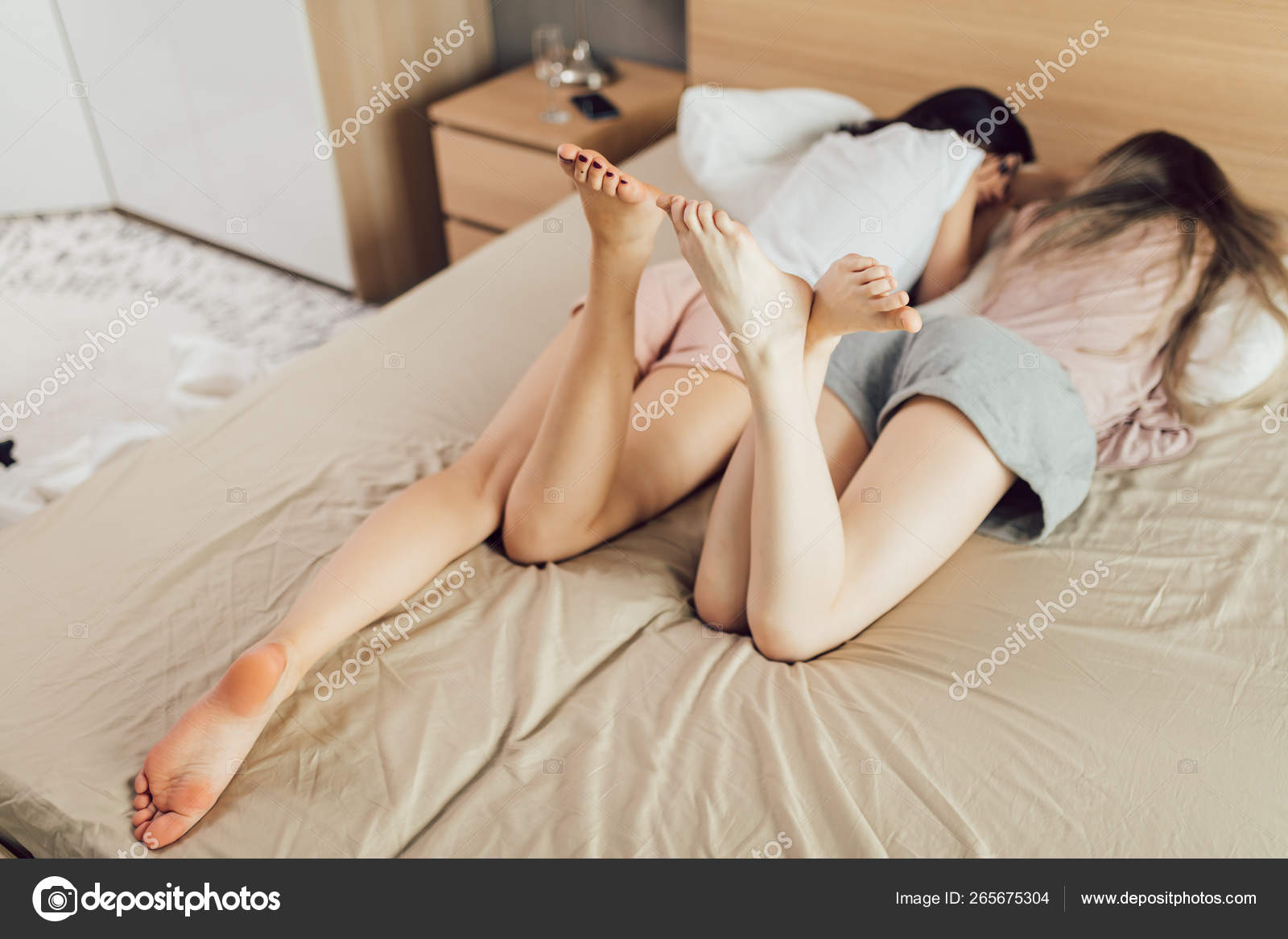 Телочка лежит на кровати позволяя подруге делать массаж стоп