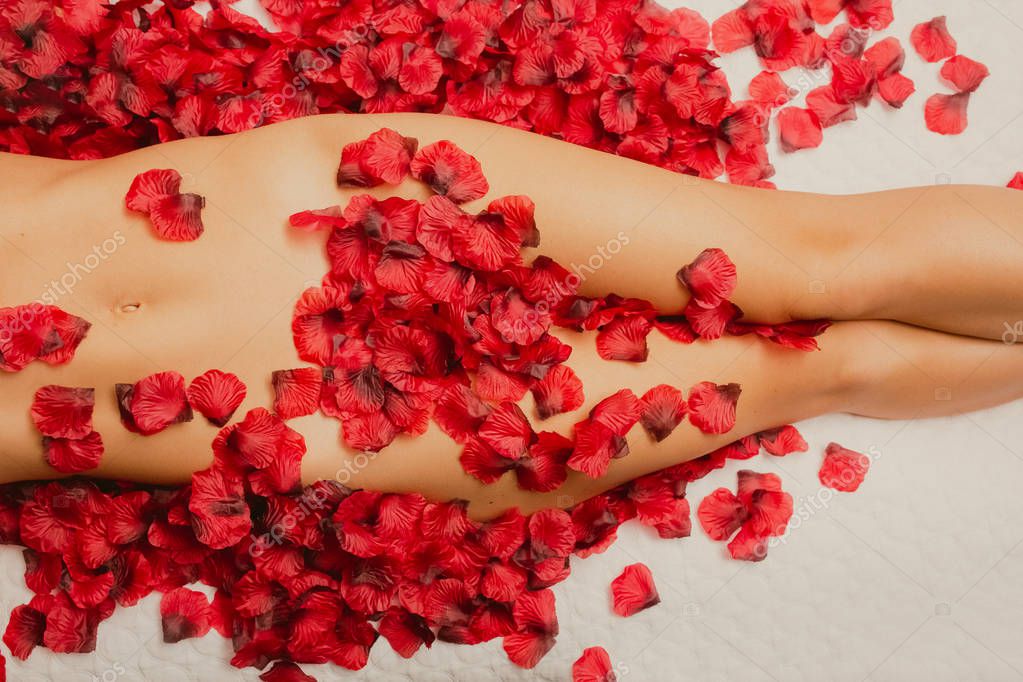 Голая девушка на кровати с лепестками роз