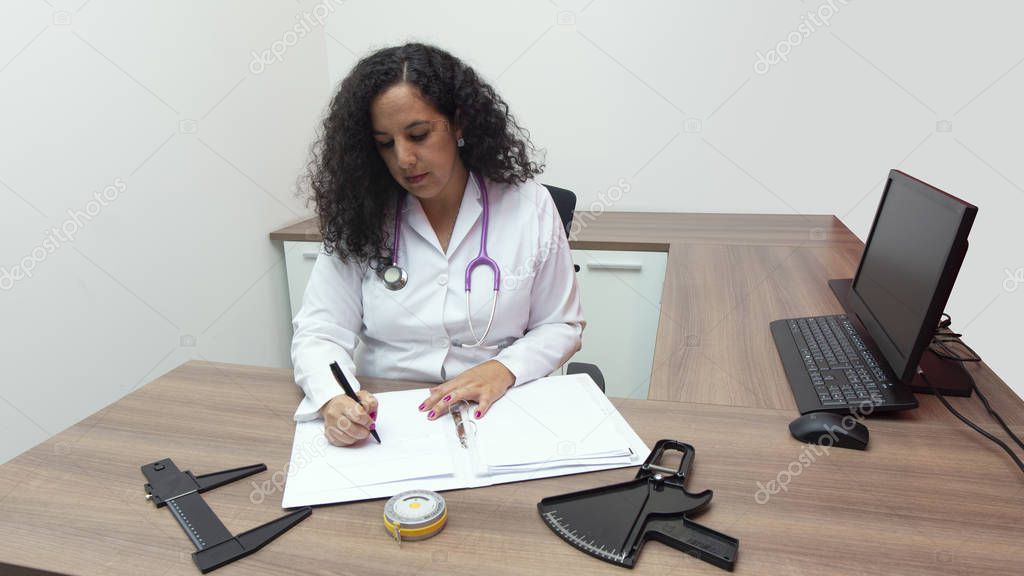 Doctora Latina Sentada Con Actitud Seria En Su Consultorio Con Estetoscopio En El Cuello