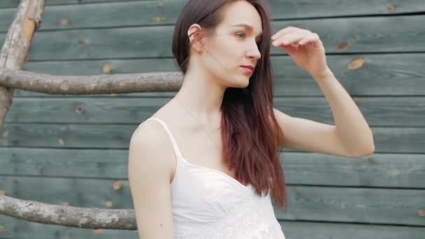 Primavera ritratto di moda di una bella giovane donna felice in abito bianco con lunghi capelli castani vicino al magazzino di legno — Video Stock