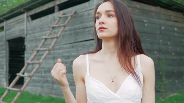 Primavera retrato de moda de uma bela mulher jovem feliz em vestido branco com cabelos castanhos longos perto do armazém de madeira — Vídeo de Stock