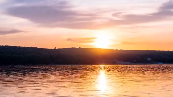Nuages légers étendus sur le ciel du soir, ciel du lac coucher de soleil time lapse shot. Disque solaire devant, se cacher derrière une bande dense de nuages, descendre jusqu'à la ligne d'horizon. Reflex sur l'eau plate — Video