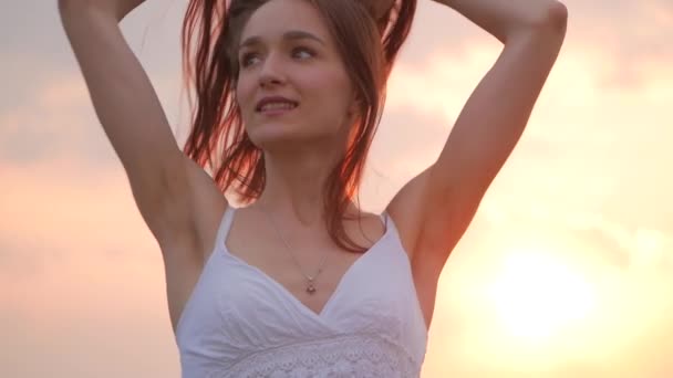 Retrato de moda de primavera de una hermosa mujer joven feliz en vestido blanco con pelo largo y castaño sobre fondo de atardecer — Vídeos de Stock