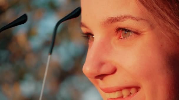 Lächelnde junge Frau setzt Sonnenbrille auf. Zeitlupe — Stockvideo