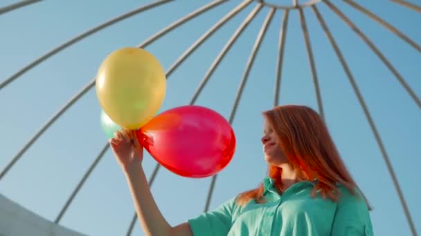 Kızıl saçlı ve iplik ve gülüyor, beyaz arka plan üzerinde renkli hava balonları güzellik kız. Güzel mutlu genç kadın Doğum günü tatil partisi. Neşeli modeli eğleniyor, kutluyor — Stok video