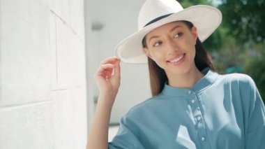 Mutlu şık sevimli genç karışık ırk kadın moda Blogger mavi yazlık elbise ve beyaz şapka yaz sokakta poz portresi, Güneş parlıyor