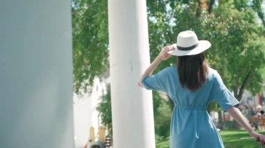 Mutlu şık büyüleyici genç yarış kadın moda Blogger yürüyüş boyunca Avrupa kentsel mavi yazlık elbise sokakta karışık ve beyaz şapka ve zevk tatil tatil macera whith pembe çiçekler seyahat