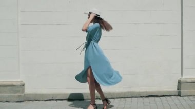 Mutlu şık büyüleyici genç yarış kadın moda Blogger yürüyüş boyunca Avrupa kentsel mavi yazlık elbise sokakta karışık ve beyaz şapka ve zevk tatil tatil macera seyahat.