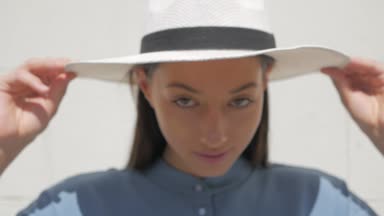 Mutlu şık sevimli genç karışık ırk kadın moda Blogger mavi yazlık elbise ve beyaz şapka yaz sokakta poz portresi, Güneş parlıyor