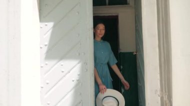 Mutlu şık sevimli genç karışık ırk kadın moda Blogger mavi yazlık elbise ve beyaz şapka ve macera seyahat tatil tatil tadını çıkarırken eski retro kapıdan dışarı çıkmak