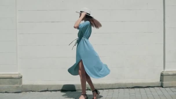 幸せなスタイリッシュな魅力的な若い混合レース女性ファッションのブロガー歩行に沿ってヨーロッパ街路青い夏のドレスと白い帽子と楽しむ休日旅行休暇の冒険 — ストック動画