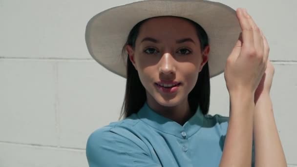 Портрет счастливой стильной очаровательной молодой смешанной расы женщина Блогер моды в синем летнем платье и белая шляпа позирует на летней улице, солнце светит — стоковое видео