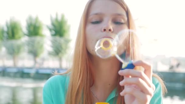 Дівчина з рудим волоссям дме мильні бульбашки — стокове відео