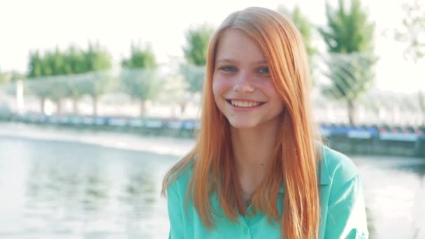 Retrato de uma jovem mulher bonita com cabelo vermelho em um parque na primavera — Vídeo de Stock