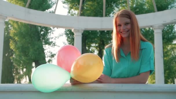 Девушка-красавица с рыжими волосами и красочными воздушными шарами, вращающимися и смеющимися на белом фоне. Поздравляю молодую женщину с днем рождения. Радостная модель веселится, празднует — стоковое видео
