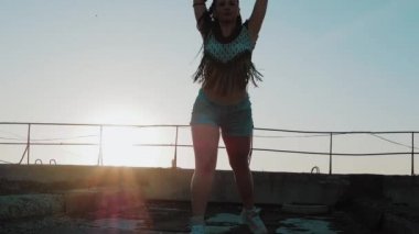 Erkek dans. siluet mutlu karışık ırk kadın uzun dreadlocks ile performans şortla günbatımı arka plan üzerinde dans.