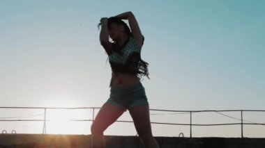 Erkek dans. siluet mutlu karışık ırk kadın uzun dreadlocks ile performans şortla günbatımı arka plan üzerinde dans.