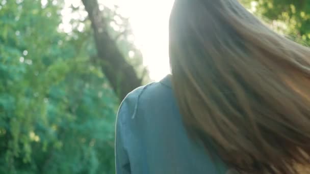 Hermosa mujer peinando el cabello al aire libre. A cámara lenta. Feliz chica atractiva calma con el pelo largo y saludable divertirse en el parque, disfrutar de la naturaleza, jugando con el viento. De cerca. Lente llamarada . — Vídeo de stock