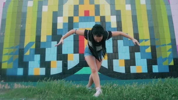 Tanzende Frau. fröhliche Mischlingshündin tanzt Performance mit langen Dreadlocks in kurzen Hosen — Stockvideo