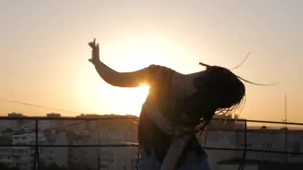 Bailarina. silueta feliz mujer de raza mixta bailando rendimiento con rastas largas en pantalones cortos en el fondo de la puesta del sol — Vídeos de Stock