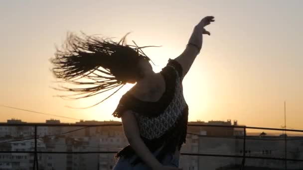 Bailarina. silueta feliz mujer de raza mixta bailando rendimiento con rastas largas en pantalones cortos en el fondo de la puesta del sol — Vídeo de stock