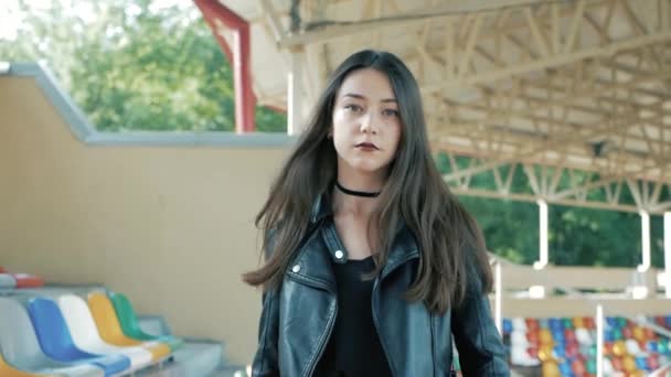 Siyah, deri ceket, uzun siyah saçlı ve ruj ile gerdanlık kolye giyen serin moda ciddi genç kadın yürüyüş — Stok video