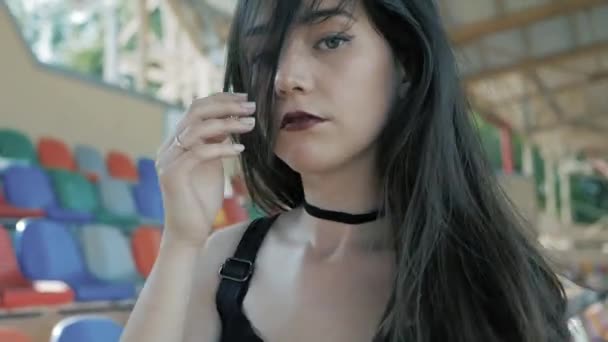 Moda cool mujer adolescente seria vistiendo de negro, chaqueta de cuero, collar de gargantilla con un largo pelo oscuro y lápiz labial — Vídeo de stock