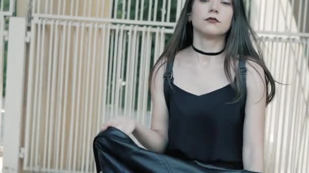 Camminare moda cool seria adolescente indossa in nero, giacca di pelle, collana girocollo con lunghi capelli scuri e rossetto — Video Stock