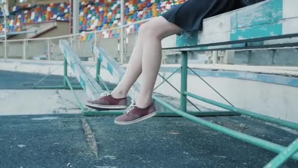 Bir kadının bacakları futbol Stadı'nda asılı olan. Kırmızı spor ayakkabı ayaklarda — Stok video