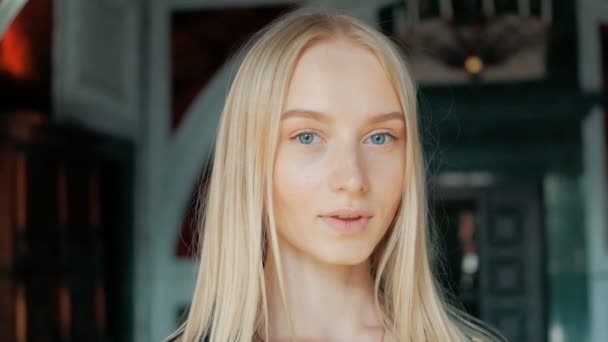 屋内のレザー ジャケットのブロンドの髪と青い目の美しい若い女性のファッションの肖像画 — ストック動画
