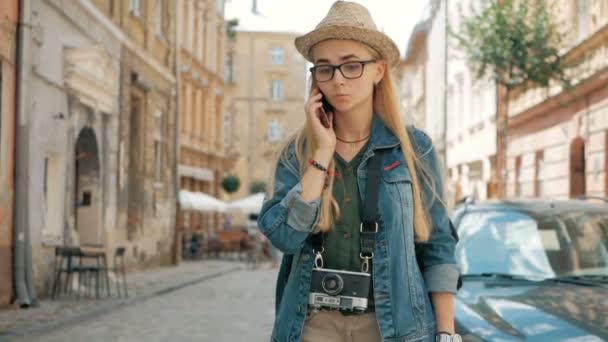 Jonge leuke toeristische is praten over de telefoon buiten, het dragen van hoed, bril — Stockvideo