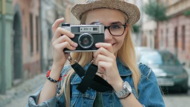Joven turista tomando una foto en cámara retro de una ciudad de vacaciones — Vídeo de stock