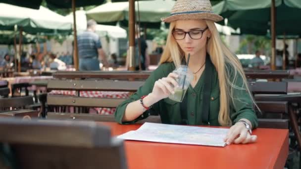 Jonge toeristische vrouw verkennen stadsplattegrond van lviv in café en drankje onderweg in Oekraïne, vakantie concept — Stockvideo