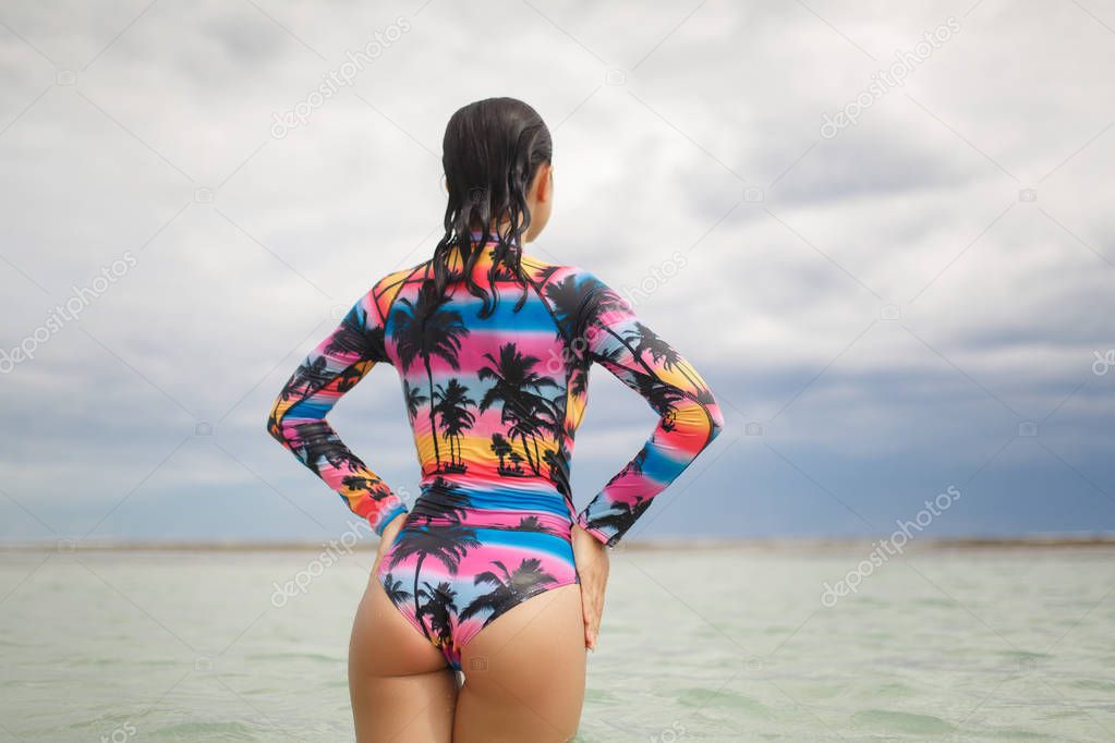 Young, sporty, sexy and beautiful girl in swimsuit resting on exotic beach in summer
