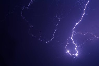 Mor ışıkta şehrin üzerinde şimşek fırtınası