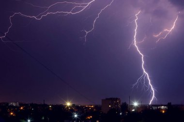 Mor ışıkta şehrin üzerinde şimşek fırtınası