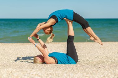 İki kadının deniz plaj fitness egzersizleri yoga yapıyor.