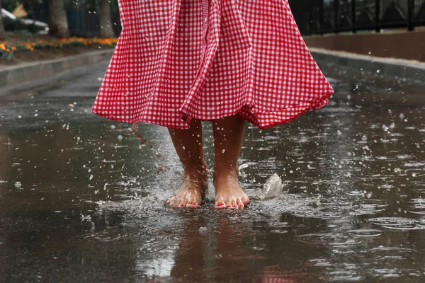 close-up of a girl\'s feet dancing in a puddle after a summer rain.