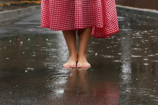 close-up of a girl's feet dancing in a puddle after a summer rain.