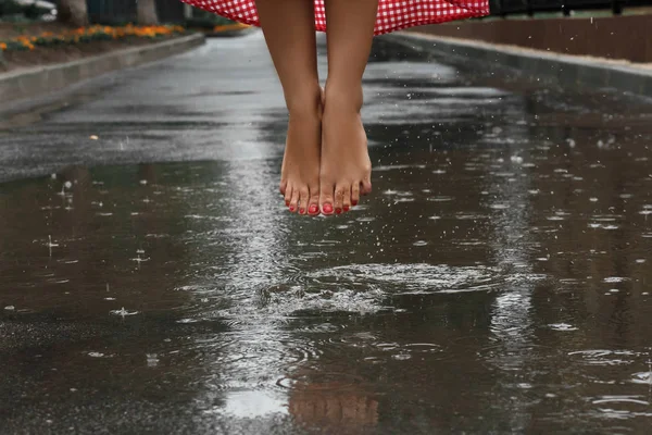 close-up of a girl\'s feet dancing in a puddle after a summer rain.