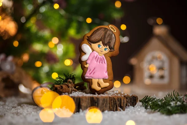 Holiday traditional food bakery. Gingerbread cute angel girl in cozy warm decoration with garland lights.