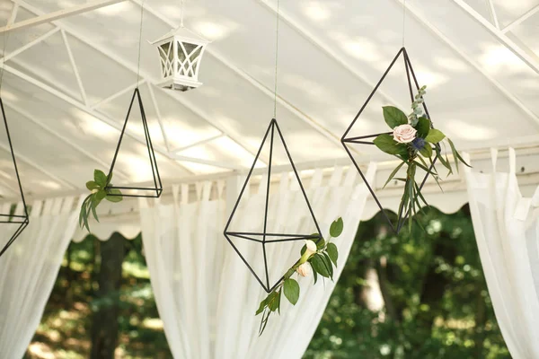 Decorative hanging cages with fresh flowers. Event flowers decoration. Wedding decor.