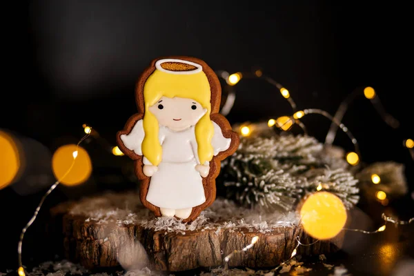 Holiday traditional food bakery. Gingerbread little cute angel girl in cozy decoration with garland lights.