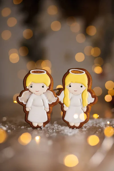 Holiday traditional food bakery. Gingerbread pair of little cute angels boy and girl in cozy warm decoration with garland lights.
