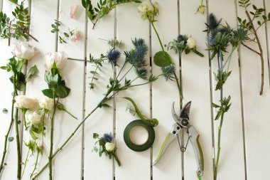 Budayıcı ve diğer çiçekçi araçları ve beyaz tahta masanın üzerinde yatan kesilerek taze çiçekler. Olay taze çiçek dekorasyon. Çiçekçi iş akışı. Düğün Ziyafet tasarım