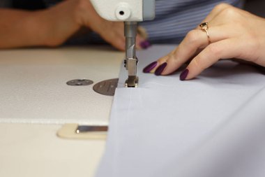 Dikiş makinesinde çalışan kadın terzinin ellerine bakın. elbise imalatı endüstrisi.