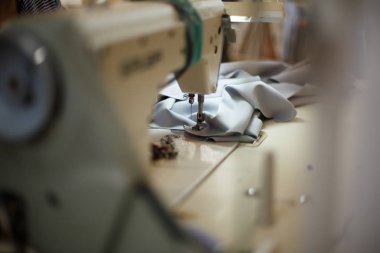 Işıklı bir dikiş makinesinin yakın çekimi. İş yeri terzisi. Dikiş endüstrisi.