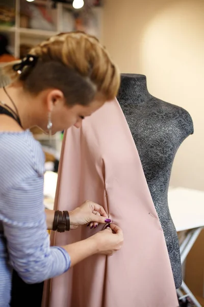 female dressmaker attach fabric to mannequin with needles. creating dress design. Tailor industry concept.